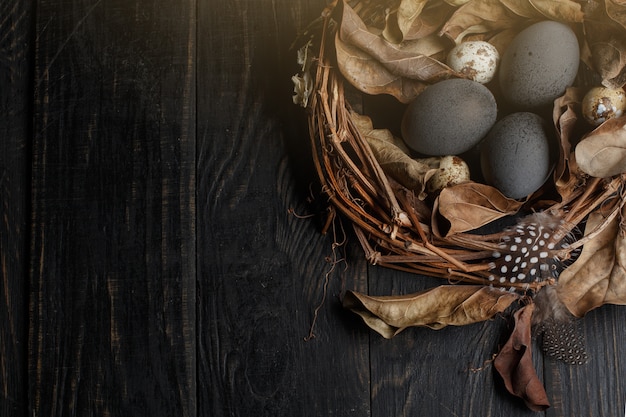 Black eggs in a nest of dry branches on a black board. Easter style.