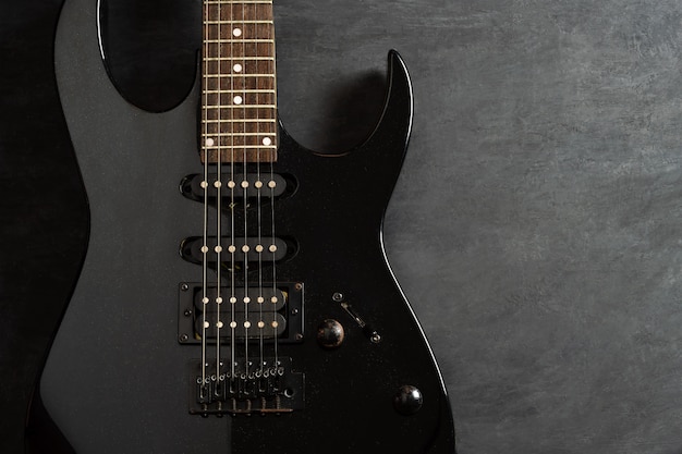 Black electric guitar on black cement floor background