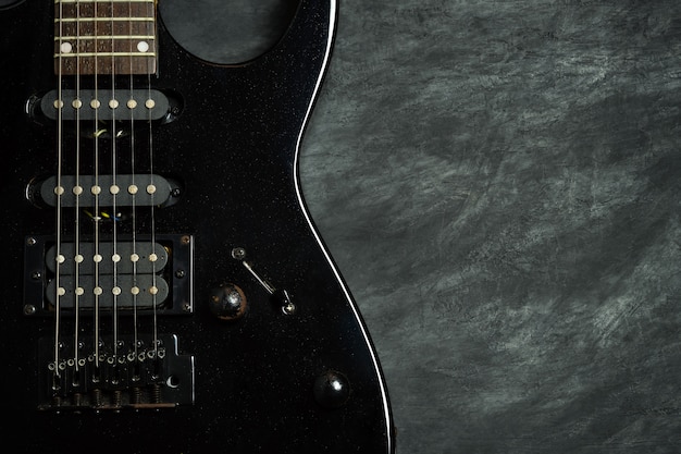 Black electric guitar on black cement floor. 