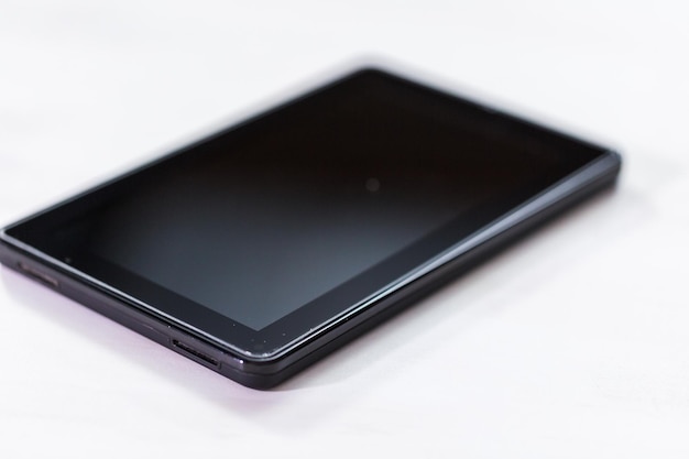 Black electronic book reader on a white table.