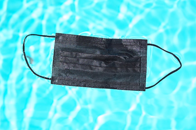 Black face mask for protection against the corona virus (COVID-19) in water of swimming pool.