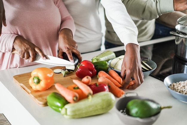 Black family cooking inside kitchen at home  Focus on left hand holding knife