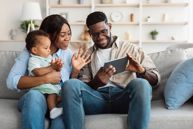 Black family having videocall using tablet waving hands