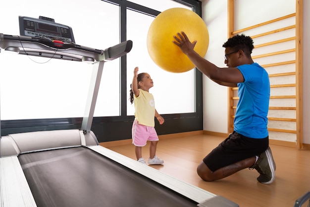 Black father and daughter exercising with fit ball