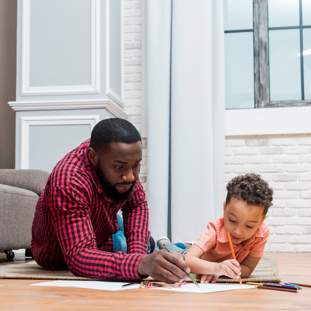 Black father and son drawing on floor