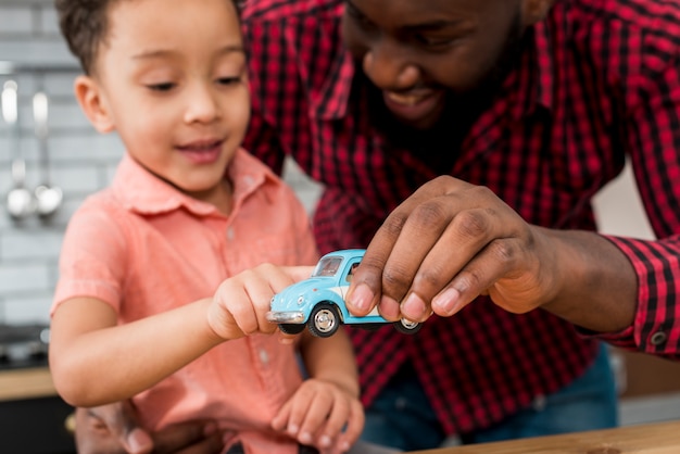 Black father and son playing with toy car