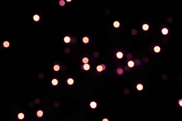 Black festive background with shining hexagonal bokeh lights.