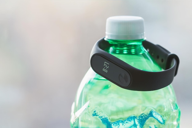 Black fitness tracker on a green bottle of mineral water