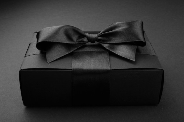 Black friday sale box gift present with ribbon bow on black conceptual design