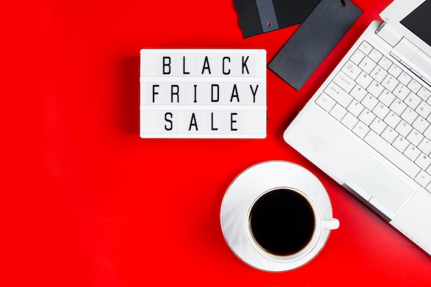 Black Friday sale concept Laptop and coffee cup on red background Banner for advertising