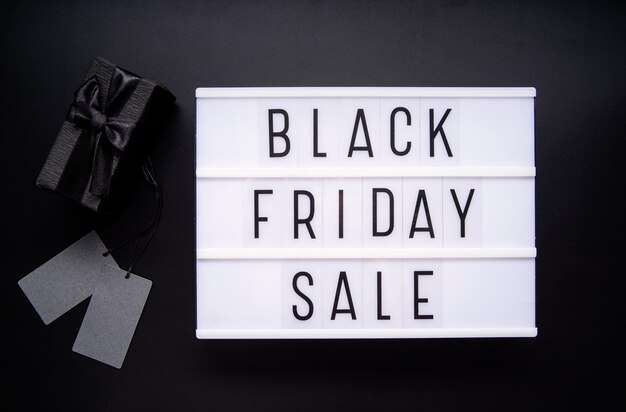 Black Friday Sale words on lightbox with cup of coffee, mobile phone and potplant