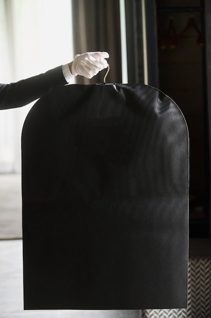 Black garment suit travel bag the hands of a hotel worker in white gloves