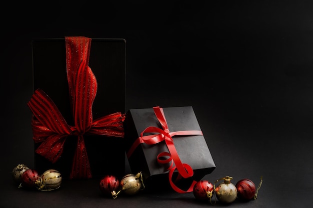 Black gift box, balls, red Christmas decorations on the dark wooden background copy space