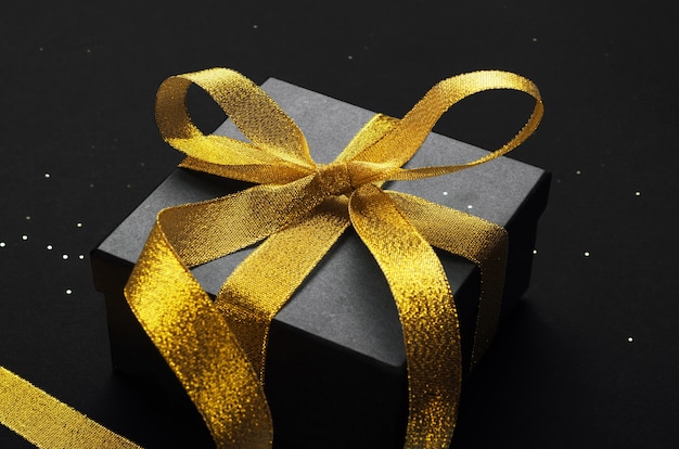  black gift box with golden bow top view.