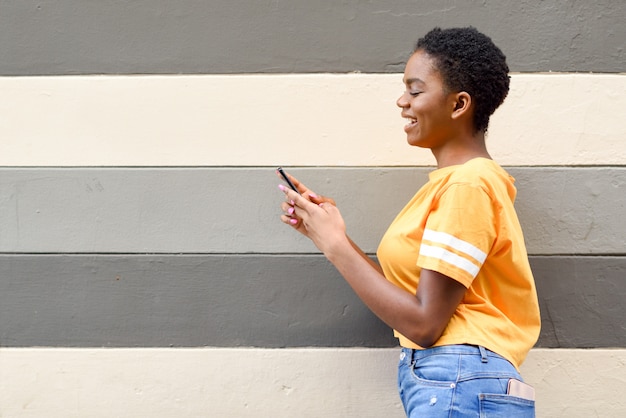 Black girl smiling and using her smart phone outdoors.