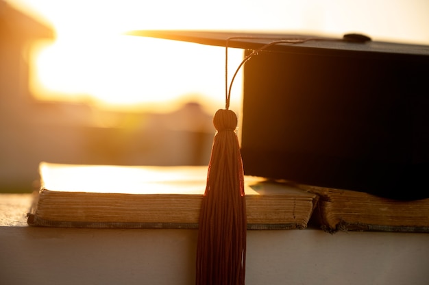 black graduation cap with brown tassels placed on books