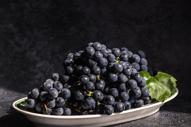 Black grapes lie on a white plate with an oval green stripe