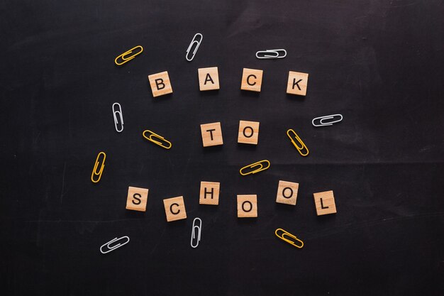 Black graphite board with the inscription of wooden letters back to school near the stationery color...