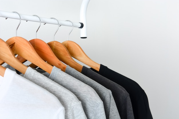 Black, gray and white color t-shirt hanging on wooden clothes hanger