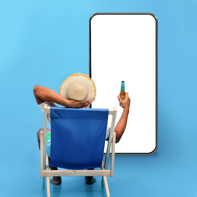 Black guy sitting in lounge chair with bottle of beer