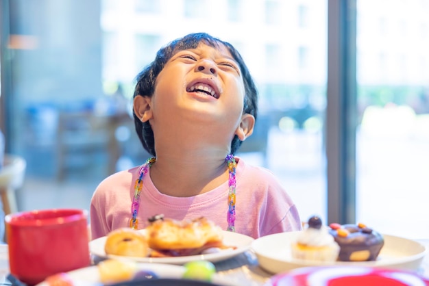 Black haired Asian boy in a pink shirt is happy eating breakfast in resort restaurant vacation