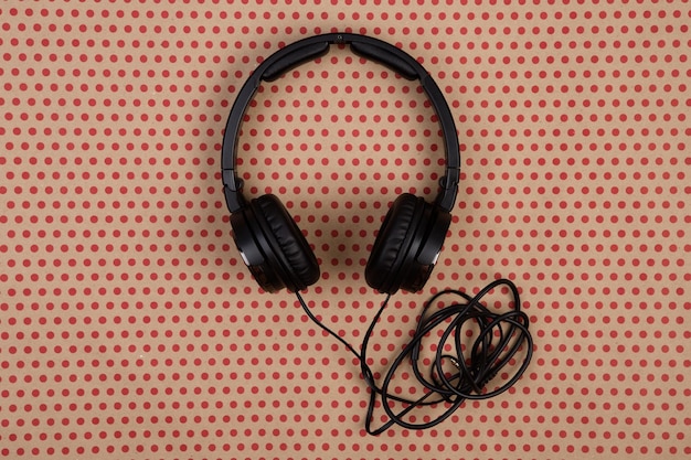 Black headphones on craft paper background in red polka dots