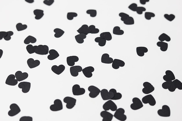 black heart shaped confetti on a white paper background pattern