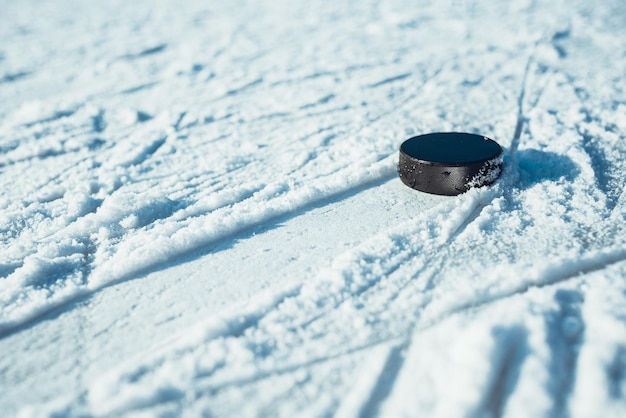 Black hockey puck lies on ice at stadium