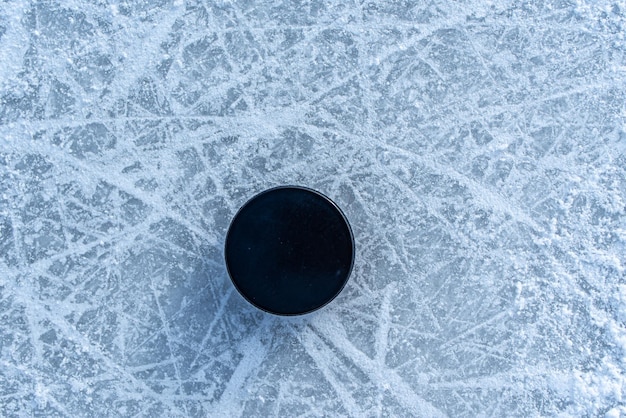 Black hockey puck lies on ice at stadium