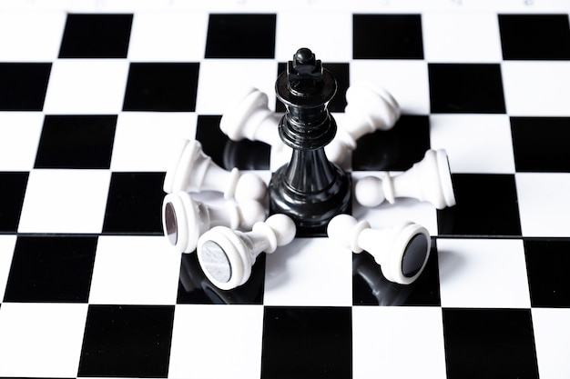 Black king chess on board with white chesses army Leader challenges planning business strategy