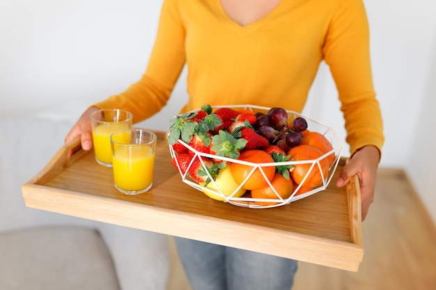 Black lady holding tray with fruits and juice indoor cropped