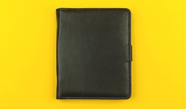 Black leather notepad on a colorful yellow office table, concept of a business diary, mockup and place for your text, top view photo