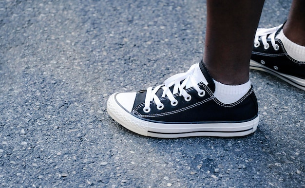 Black legs of the female protester during a manifestation of the black lives matter movement Millennial's feet wearing black canvas casual shoes on urban asphalt road Human rights copy space