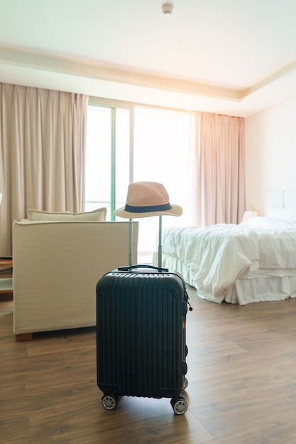 Black Luggage with hat in modern hotel room after door opening Baggage for Time to travel service journey trip summer holiday and vacation concepts