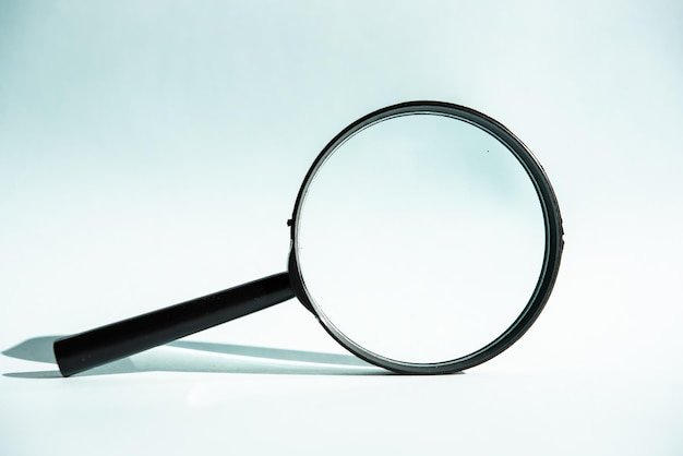 A black magnifying glass on a blue background concept of search research looking for something