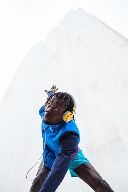 Photo black male athlete wearing headphones and dressed in sportswear, stretching before starting to exerc