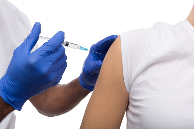 Black male hand in blue gloves holding a plastic syring with liquid for injection isolated on white background. Health care, treatment concept