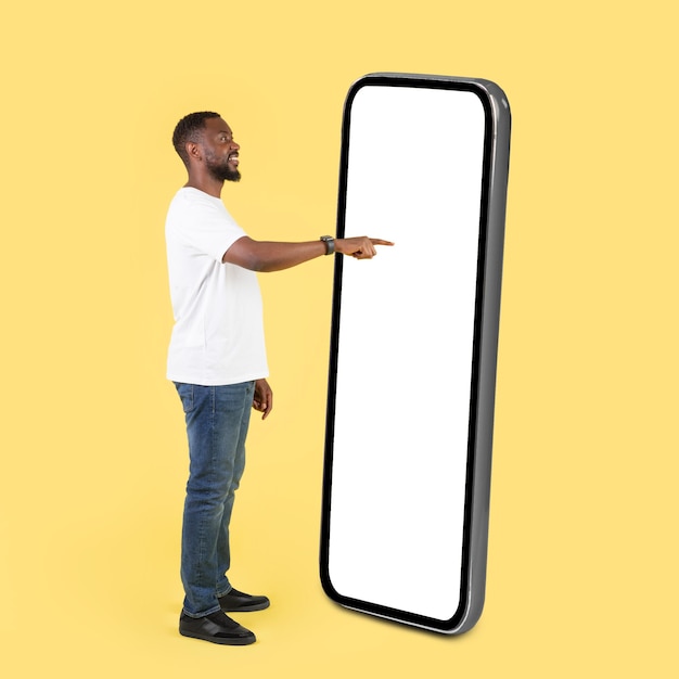 Black Male Using Cellphone With Big Screen Over Yellow Background