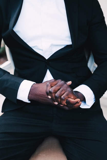 Black man in a business suit sitting in a chair, wedding concept. 