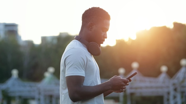 Black man looks at smartphone screen at back sunlight