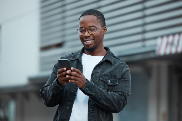 Black man phone and social media in city reading text message or communication on social network app African American person chat conversation and happy on 5g mobile smartphone in Atlanta smile