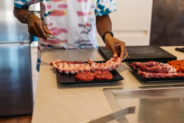 Black man prepares trays of meat for a barbecue