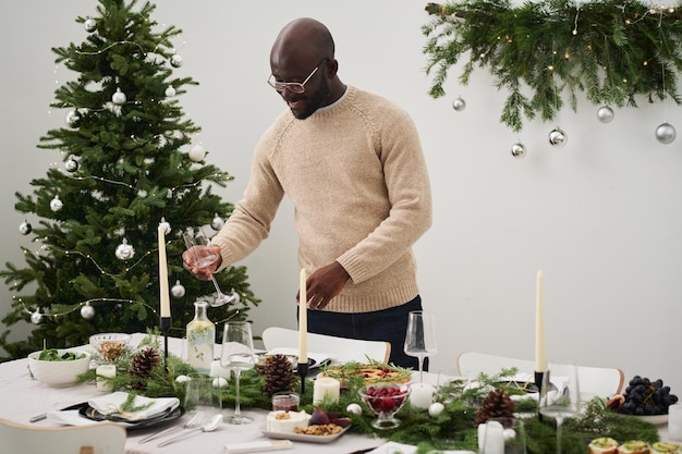 Black Man Putting Tableware on Christmas Table