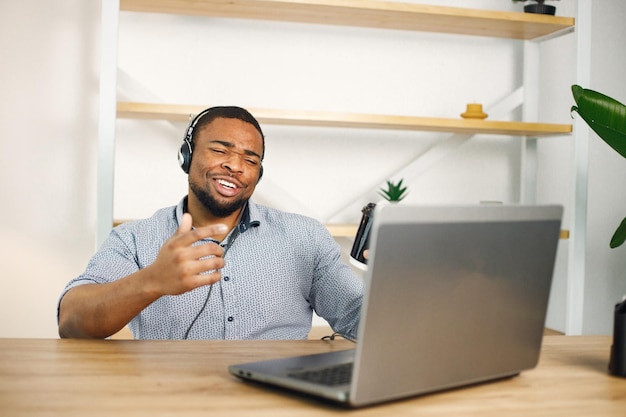 Black man sitting in office wearing a earphones and make a video call