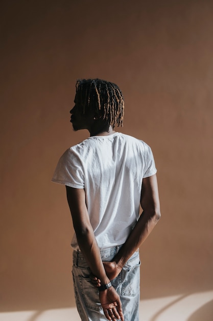 Black man standing by a beige background