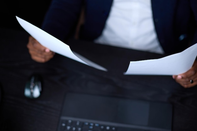 Black man studies documents on two sheets that he holds in his hands