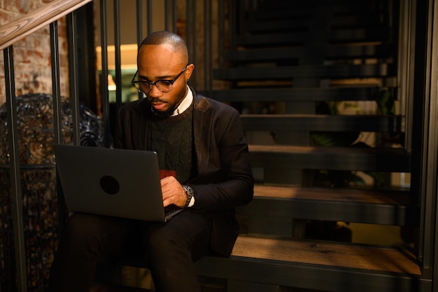 A black man works at a laptop closeup of his face video conferences