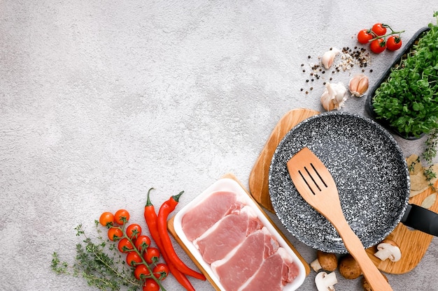 Black marble frying pan with products on grey table background top view