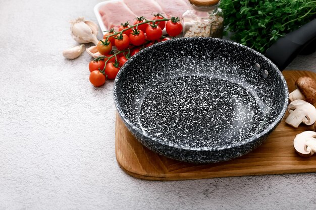 Black marble frying pan with products on grey table background top view