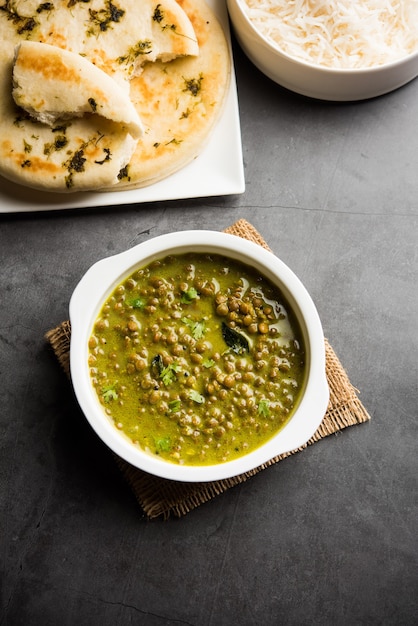 Black Masoor Dal fry or Dhaba Style Sabut Red Lentil dhal tadka in green curry, served in a bowl. selective focus